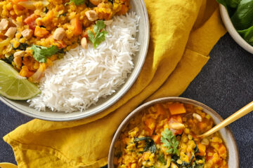 photo culinaire d'un dahl de lentilles aux épinards avec des carottes et servi avec du citron vert et de la coriandre