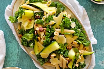 photo culinaire d'une salade de pâtes au citron, noisettes et parmesan avec des courgettes, du basilic et du chou kale