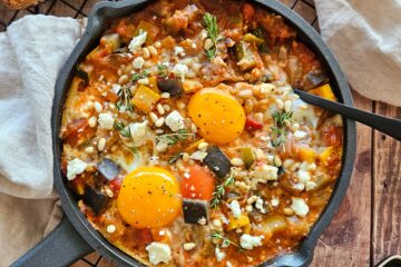 photo culinaire d'un plat de ratatouille aux œufs et à la feta avec des pignons de pin et du thym