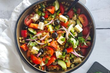 photo culinaire de salade de lentilles à la grecque avec des concombres, des poivrons, des tomates, de la feta, des olives, de la menthe et du persil
