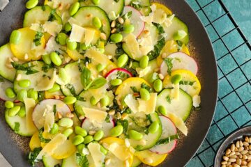 photo culinaire d'un carpaccio de légumes printaniers au citron confit et parmesan avec des pignons de pin, de la menthe et du basilic