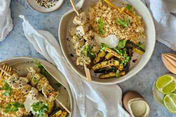 photo culinaire de brochettes de poulet au tahini, sumac et citron avec du yaourt grec et de l'ail servi avec des frites de courgettes et du couscous