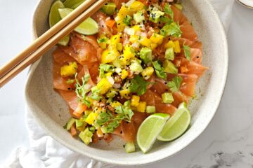 photo culinaire d'un sashimi de saumon et sauce salsa avec de l'avocat, des concombres, des tomates et de la mangue avec coriandre et citron vert
