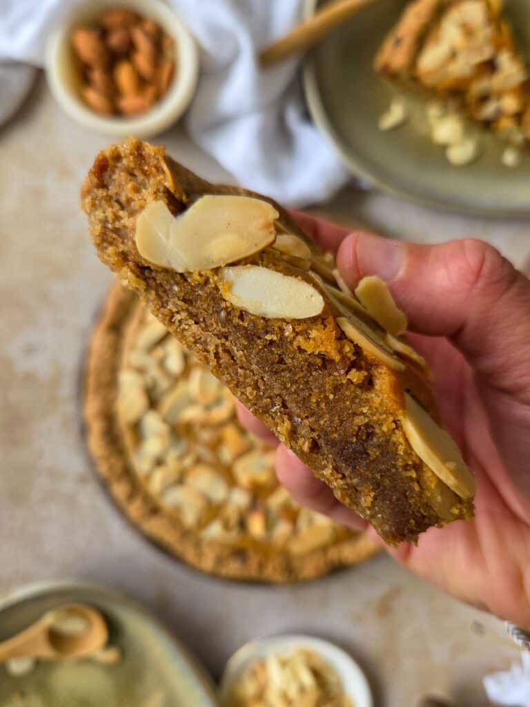 photo culinaire d'une part de cookie cake à la crème d'amandes avec des amandes effilées, une galette des rois version cookie