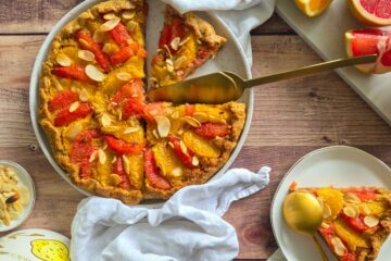 photo culinaire d'une tarte aux agrumes et crème d'amande avec des segments d'orange et de pamplemousse et des amandes effilées