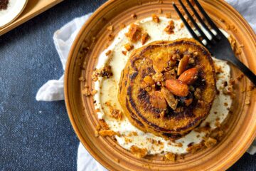 photo culinaire de pancakes à la patate douce et aux épices servis sur un lit de skyr et avec du granola et du sirop d'agave