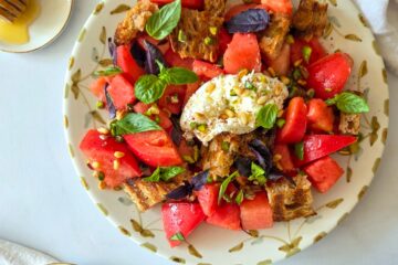 photo culinaire d'une salade de tomates, pastèque et burrata avec des pistaches, pignons de pin et basilic