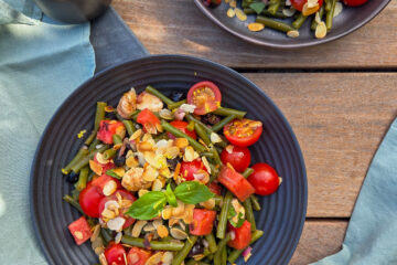 photo culinaire d'une salade de haricots verts, pastèque et mozzarella avec des tomates cerises, du basilic et des amandes effilées