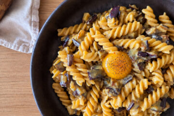 photo culinaire de pâtes aux aubergines façon carbonara avec du poivre et du pecorino romano et un jaune d'oeuf