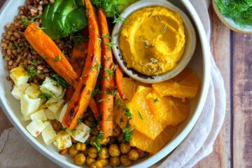 photo culinaire d'un bowl de carottes rôties, sarrasin et pois chiches avec de la feta, de l'avocat et un dip de carottes à l'orange