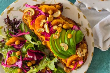 photo culinaire d'une tartine vegan carotte, orange, chou rouge et avocat avec des pois chiches grillés et des noix de cajou grillées servie avec une salade